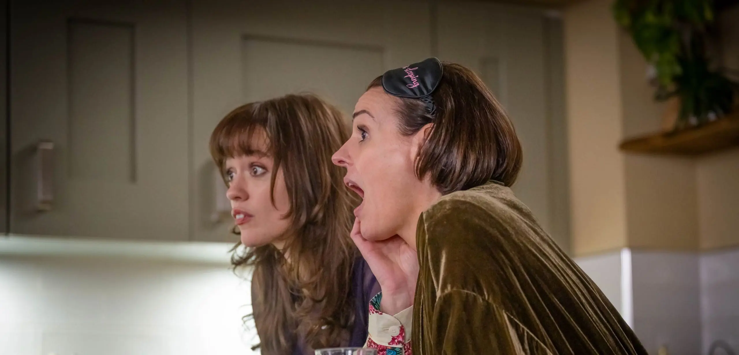 Two people talking indoors at a kitchen table
