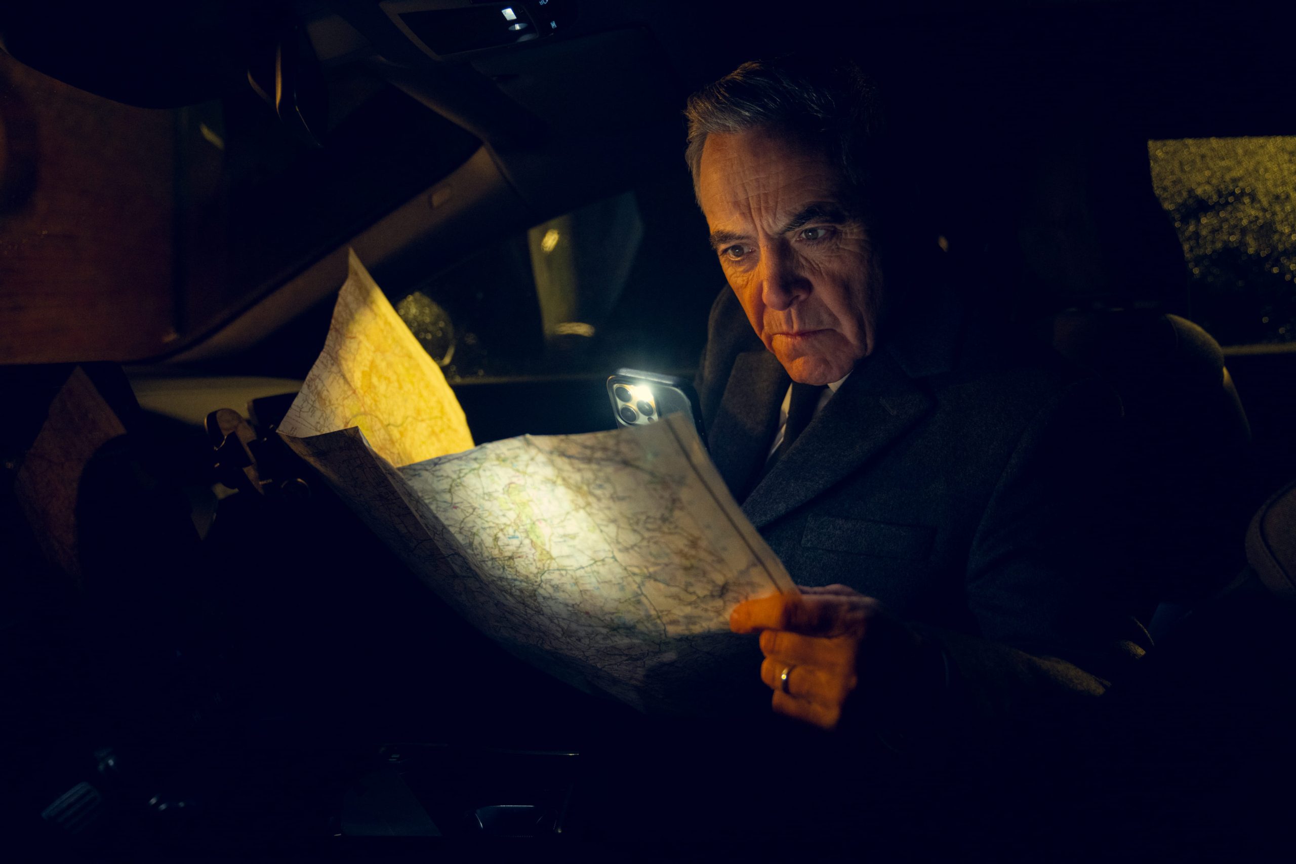 Man investigating map in front seat of car